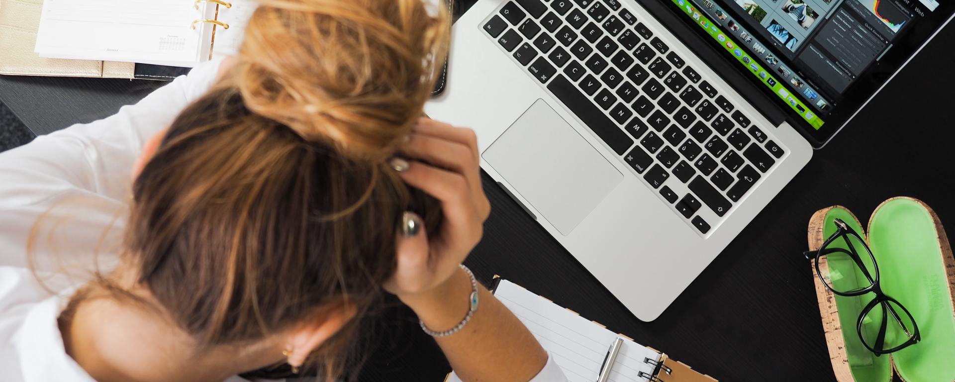 woman holding head in front of laptop
