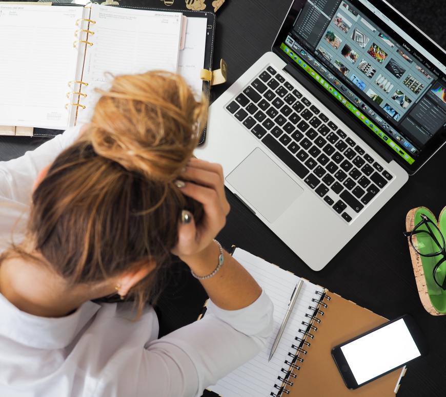 woman holding head in front of laptop